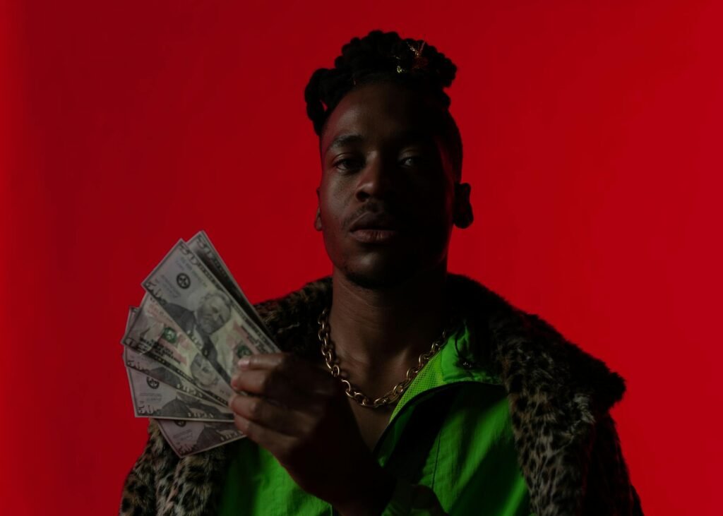A fashionable man in a green jacket holds dollars, exuding wealth and style.