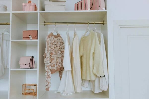 Neat closet showcasing white and pink clothes and accessories for a chic, clean look.